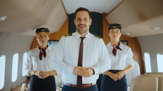 Confident airplane captain and two female flight attendants standing inside a luxurious private jet, smiling and looking at the camera, ready to provide excellent first-class airline service