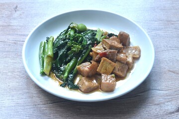 fried Kailaan Chinese kale and dice tofu dressing soy sauce vegetarian food on plate