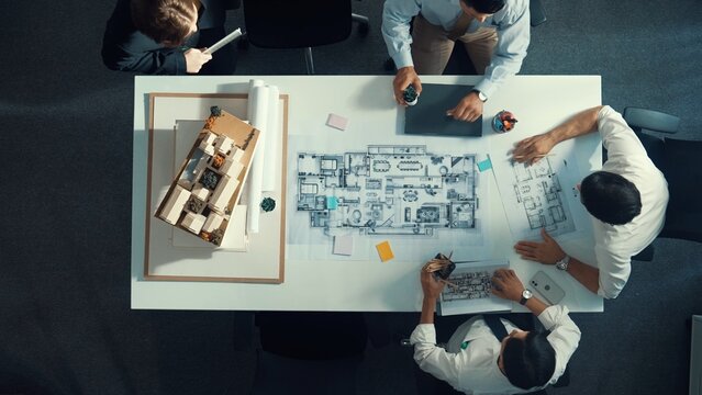 Top down aerial view of project manager using laptop to analysis building construction. Aerial view of engineer planning and writing at sticky note while brainstorming house structure. Alimentation.