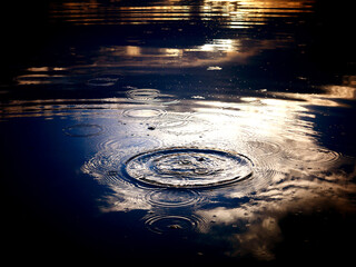 Low key image of water surface with sunset sky reflections