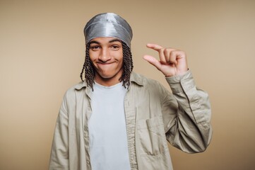 Young man with braided hair wearing a durag, gesturing small size.