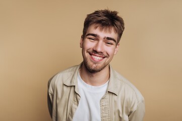 Obraz premium Smiling young man with a beard against a beige background.