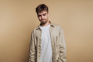 Young man with a neutral expression in casual clothing against a beige background.