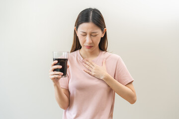 Acid reflux disease, suffer asian young woman, girl hand holding a glass of cola, have symptom...