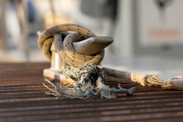 Frayed Rope Securely Fastened to a Metal Cleat on a Wooden Dock, Reflecting Strength, Resilience, and Nautical Heritage