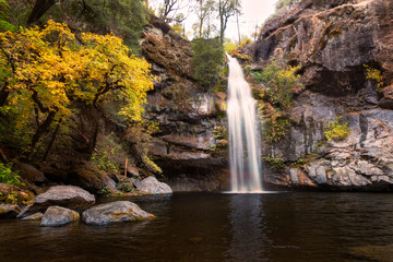 Potem Falls waterfall cascading into a tranquil pool surrounded by autumn foliage in Shasta County, California.