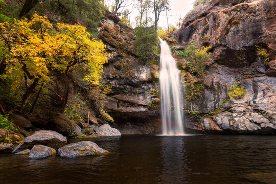 Potem Falls waterfall cascading into a tranquil pool surrounded by autumn foliage in Shasta County, California.