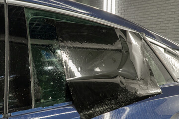 Male car service worker glue window tinting in luxury car detailing car repair the concept of love for cars and protection. Applying tinting foil on a car window in the tuning studio close-up. 