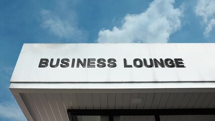 Business Lounge word sign elegantly displayed on the sophisticated corporate or airport facade beneath a clear blue sky, signifying a comfortable, exclusive space for professional relaxation - Powered by Adobe