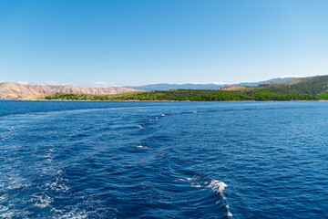 Scenic ocean view with distant green hills under clear blue sky