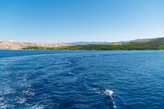 Scenic ocean view with distant green hills under clear blue sky