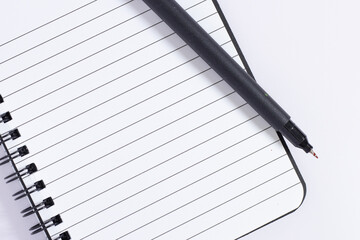 Close-up photo of a writing note with a pen in a spiral notebook placed on a white background....