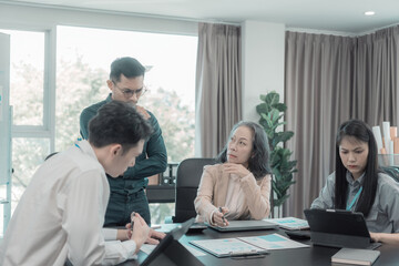 Group of business people discussing charts and graphs showing results of teamwork of colleagues working together at desks in office and discussing documents.