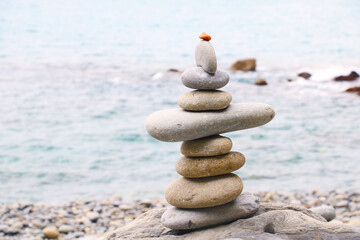 Balanced stones stacked on the beach with calm sea background, symbolizing harmony, balance, and mindfulness in nature. Perfect concept for wellness, meditation, and tranquility themes.