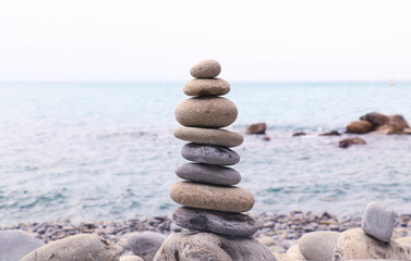 Balanced stones stacked on the beach with calm sea background, symbolizing harmony, balance, and mindfulness in nature. Perfect concept for wellness, meditation, and tranquility themes.