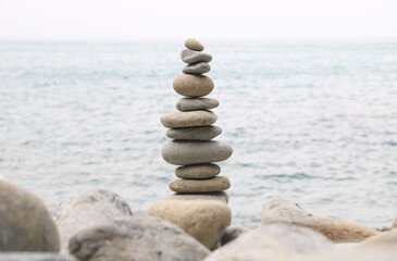 Balanced stones stacked on the beach with calm sea background, symbolizing harmony, balance, and mindfulness in nature. Perfect concept for wellness, meditation, and tranquility themes.