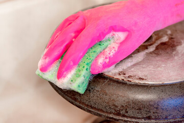 dirty frying pan, kitchen sponge, glove. hand, washing frying pan.