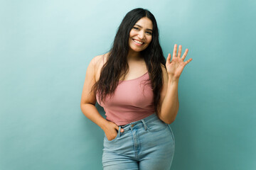Happy hispanic woman greeting, waving hand, smiling face
