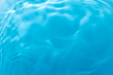 Macro blue water surface,Water surface from falling drops of water. Radial waves from a rain on water. Top view circles and rings on the puddle.