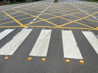 Pedestrian Crosswalk and Yellow Grid Road Markings on Asphalt