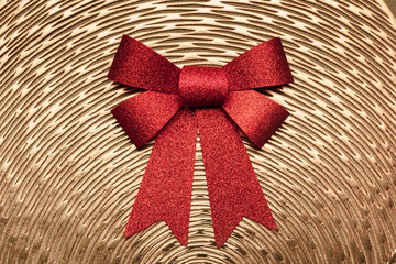 A large red bow on a gold textured background.