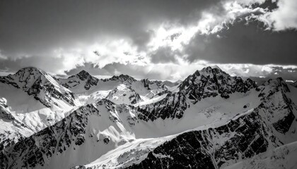 Dramatic Black and White Snow Capped Mountain Range Under Stormy Clouds With Sun Rays Breaking Through