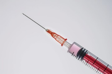 Syringe with Red Liquid: A close-up view of a syringe filled with red liquid, a symbol of modern medicine and scientific progress, ready for administration.