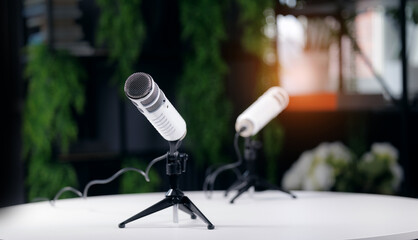 White podcast microphones on tripod stands in modern studio setting