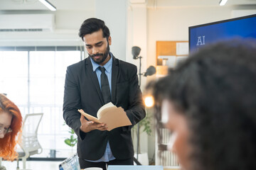 Multi-ethnic business team in office meeting, reviewing documents and brainstorming innovative...