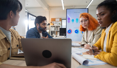 Multi-ethnic business team in office meeting, reviewing documents and brainstorming innovative...