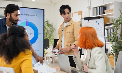 Multi-ethnic business team in office meeting, reviewing documents and brainstorming innovative...