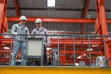 Engineers inspecting equipment and discussing maintenance procedures inside a modern industrial factory. Safety, teamwork, and production quality control in a manufacturing plant.