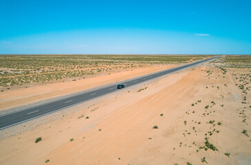 Stretch of highway through barren desert landscape under clear blue sky in remote location