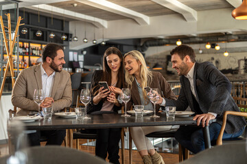 Friends enjoying a meal together at a restaurant, looking at a phone