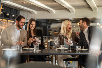 Friends laughing and using phones at a restaurant table