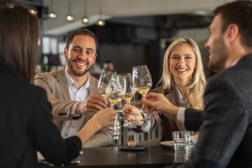 Friends toasting with wine glasses at a restaurant, celebrating together