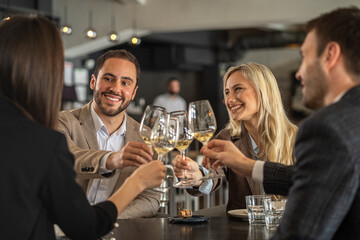 Friends toasting with wine glasses at a restaurant, celebrating together