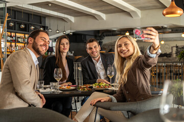 Friends taking a selfie at a restaurant during a social gathering