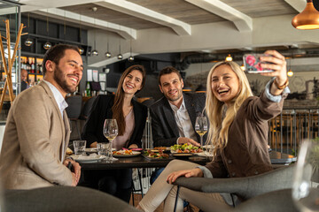 Friends taking a selfie while enjoying a meal at a restaurant