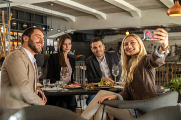 Friends enjoying a meal and taking a selfie at a restaurant