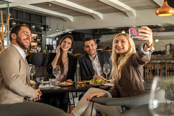 Friends taking a selfie while enjoying a meal at a restaurant