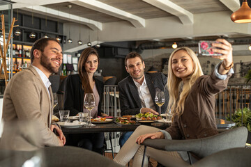 Friends enjoying a meal and taking a selfie at a restaurant