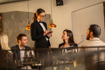 Waitress taking an order from customers at a restaurant table