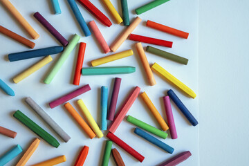 Different colorful oil pastel crayons on white paper. Flat lay, copy space