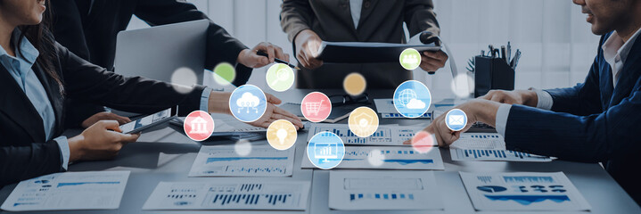 A diverse business team engages in a collaborative meeting, analyzing data and discussing strategies as digital icons illustrate key concepts for innovation. Trope