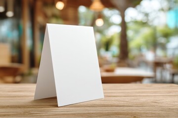 Front view of white, blank, empty menu card. Table stand layout. Blurred coffee shop background, restaurant interior. Mock-up template design for text or graphic decoration display. Paper menu holder