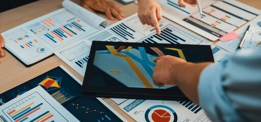 A diverse team collaborates over charts and digital tools during a strategy meeting, demonstrating...