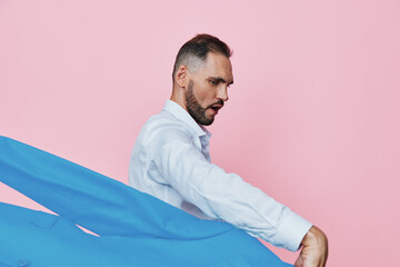 Professional man in business attire stands before a solid pink background, his face showing focus...