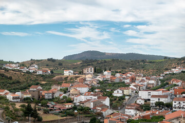 Obraz premium Vista Panorâmica de Freixo de Espada à Cinta com o aglomerado urbano e as encostas verdejantes, destacando uma edificação religiosa no alto da colina em Portugal