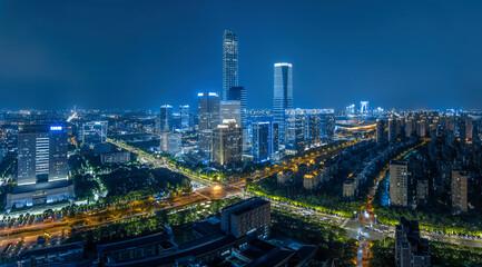 Fototapeta premium Aerial view of the modern urban cityscape with heavy traffic on the highway and illuminated buildings at night in Suzhou, China.